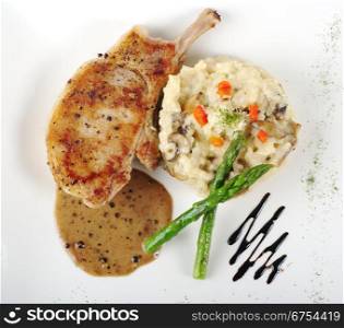 Risotto, green asparagus and meat with gravy on a garnished white plate photographed from above . Risotto, Asparagus and Meat