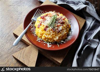 Risotto with pumpkin and bacon on a dark wooden table .. Risotto with pumpkin and bacon on a dark wooden table