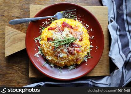 Risotto with pumpkin and bacon on a dark wooden table . Top view .. Risotto with pumpkin and bacon on a dark wooden table. Top view