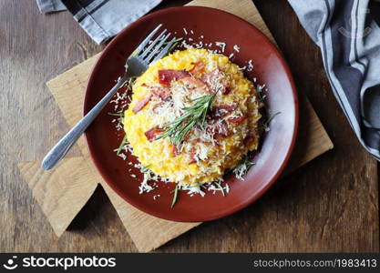 Risotto with pumpkin and bacon on a dark wooden table . Top view .. Risotto with pumpkin and bacon on a dark wooden table. Top view