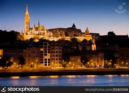 River city view of Budapest at evening in Hungary with illuminated Matthias Church on Buda hill.