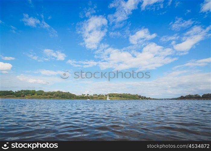 River landscape with a sailboat in the water and blue sky