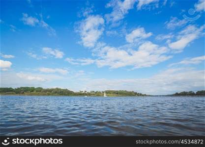 River landscape with a sailboat in the water and blue sky
