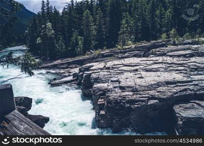 River running in rocky scenery with pine trees