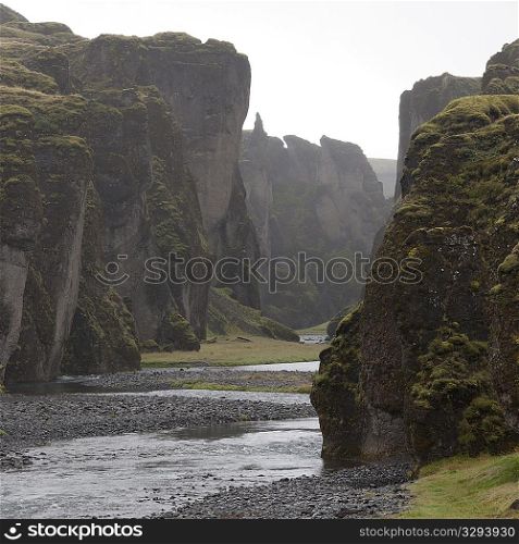 River running past steep rugged cliffs
