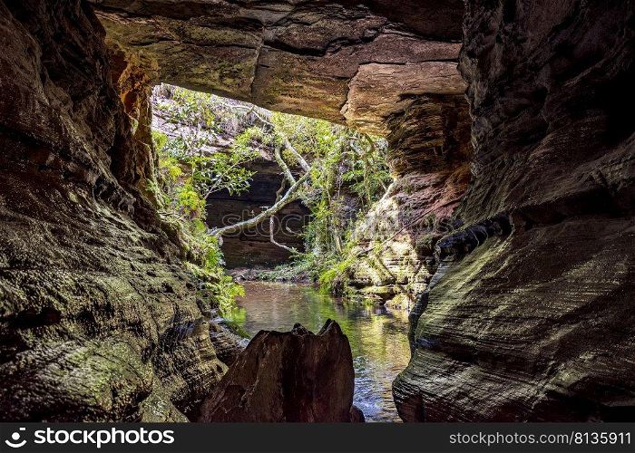 River running through stone cave in Carrancas rainforest in Minas Gerais, Brazil. River running through stone cave in Carrancas and vegetation