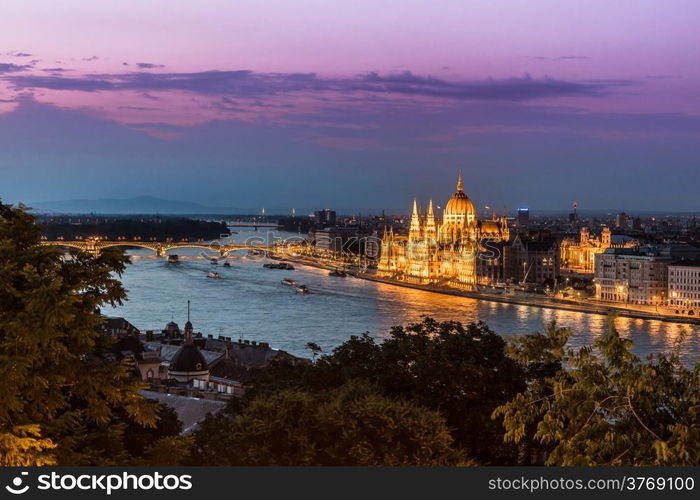 River view of Budapest at evening, illuminated Chain Bridge and Parliament Building.