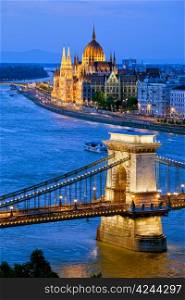 River view of Budapest at evening, illuminated Chain Bridge and Parliament Building.