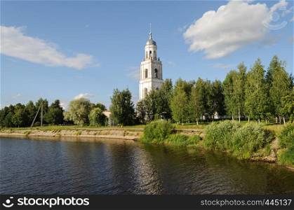 Riverbank with old bell tower in Poshekhonye, Yaroslavl region, Russia. Sunny summer day.