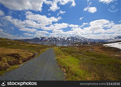 Road across the snowy landscape in Norway, summertime