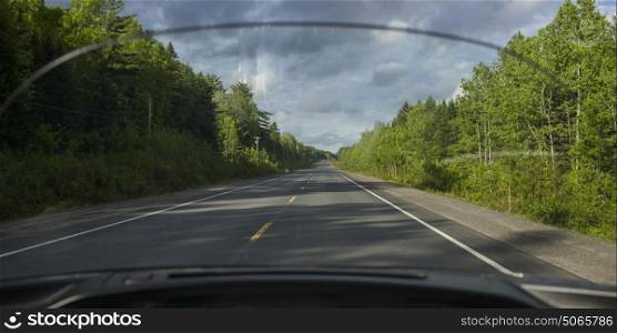 Road amidst trees seen through car windscreen, Doaktown, New Brunswick, Canada