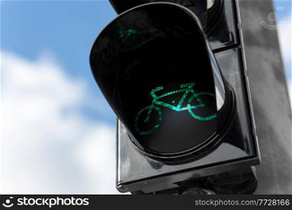 road and signals concept - close up of green traffic light for bicycle over blue sky. green traffic light for bicycle over blue sky