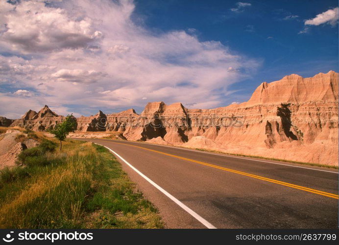 Road by hillocks against sky