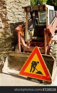 Road construction sign near an earth mover, Vernazza, La Spezia, Liguria, Italy