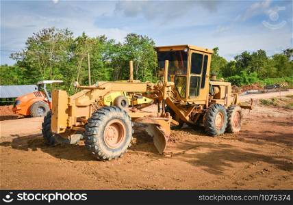Road construction with motor grader / yellow of modern grader with wheel tractor working on construction site