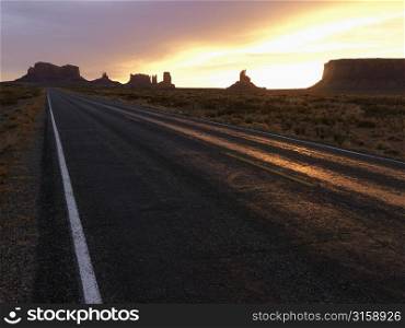Road going through desert and sunset