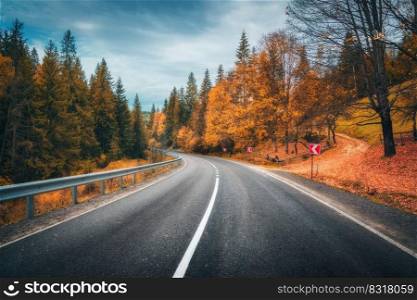 Road in autumn forest at sunset. Beautiful empty mountain roadway, trees with red foliage, overcast sky. Landscape with road through the woods in fall. Travel in europe. Road trip. Transportation