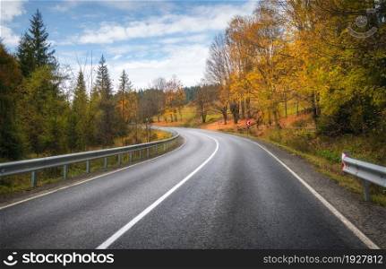 Road in autumn forest. Beautiful empty mountain roadway, trees with orange foliage and overcast sky. Landscape with asphalt road through the woods in fall. Travel in europe. Road trip. Transportation