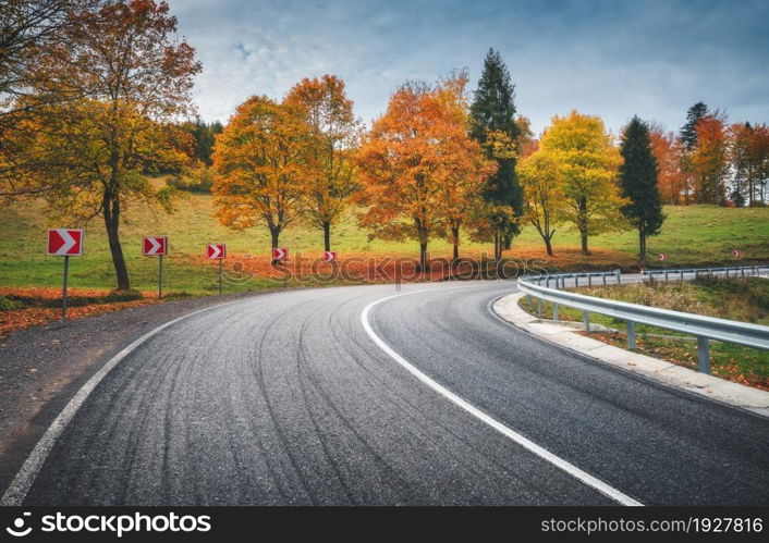 Road in autumn forest. Beautiful empty mountain roadway, trees with orange foliage and overcast sky. Landscape with asphalt road through the woods in fall. Travel in europe. Road trip. Transportation