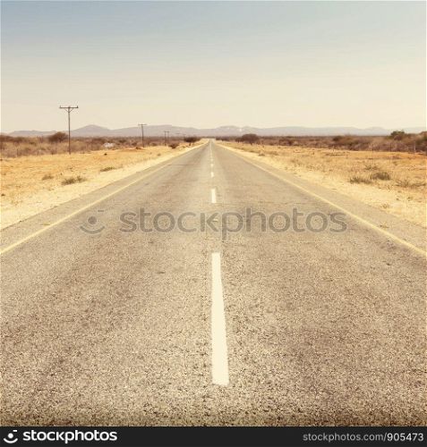 Road in Botswana, Africa stretching off into the distance under a blue sky with retro Instagram style filter effect