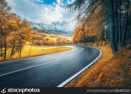 Road in mountains at sunny day in golden autumn. Dolomites, Italy. Beautiful roadway, orange tress, high rocks, blue sky with clouds. Landscape with empty highway through the mountain pass in fall