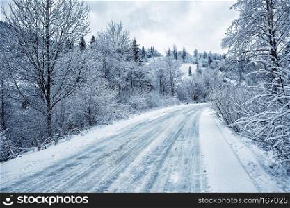 Road is among the snow-covered trees in the mountains. Winter landscape. The concept of travel.. Road is among the snow-covered trees in the mountains