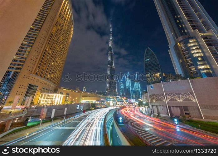 Road or street to Burj Khalifa in Dubai Downtown skyline and highway, United Arab Emirates or UAE. Financial district and business area in smart urban city. Skyscraper buildings at night.