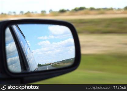 Road reflecting in the sideview mirror of a car