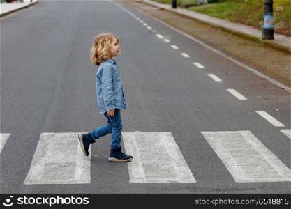 Road Safety Education. Little boy crossing alone on the road