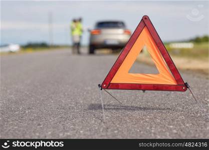 road sign, emergency and traffic concept - warning triangle over broken car