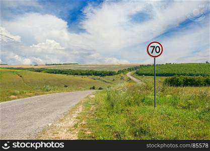 Road sign limiting speed on a country road. Bright sunny day.