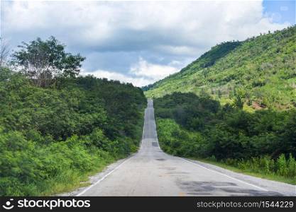 Road to mountain / A long straight road leading towards a nature green tree on the mountains , Asphalt road in Thailand