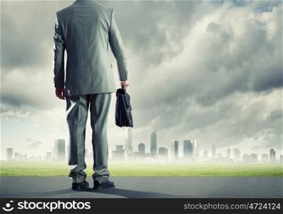 Road to success. Back view of businessman on road with suitcase in hand
