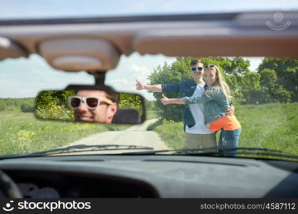 road trip, hitchhike, travel, gesture and people concept - happy couple hitchhiking and stopping car at countryside road