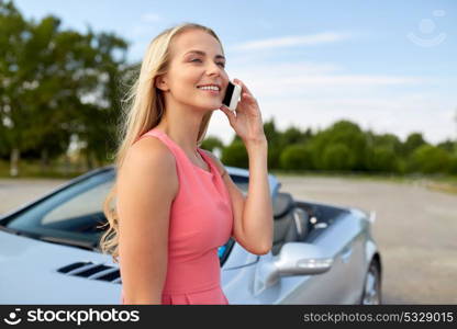 road trip, technology and communication concept - happy young woman calling on smartphone at convertible car. woman calling on smartphone at convertible car