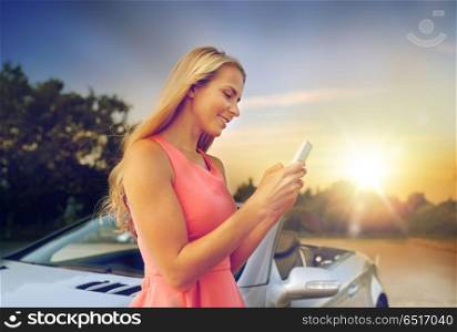 road trip, technology and communication concept - happy young woman with smartphone at convertible car. young woman with smartphone at convertible car. young woman with smartphone at convertible car