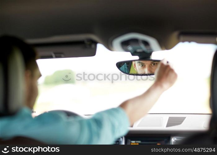 road trip, transport and people concept - man driving car adjusting rearview mirror