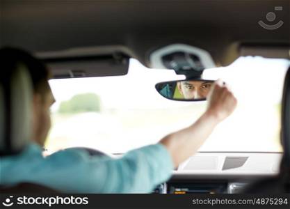 road trip, transport and people concept - man driving car adjusting rearview mirror