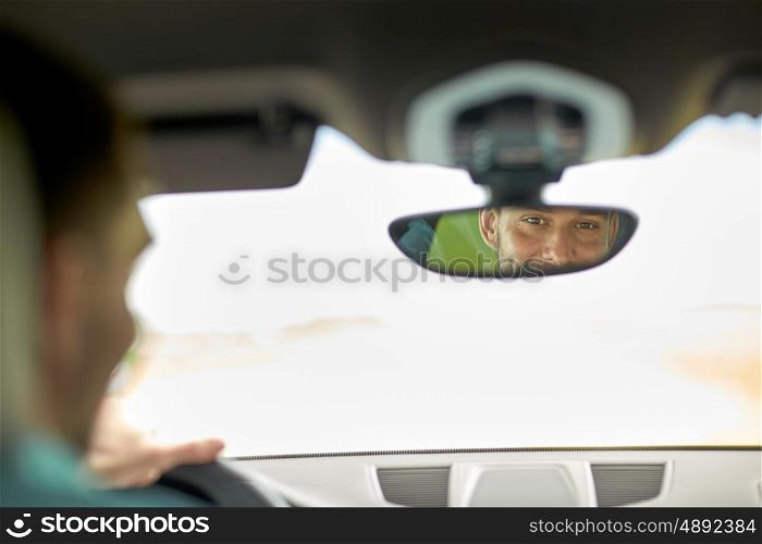 road trip, transport and people concept - rearview mirror reflection of man driving car