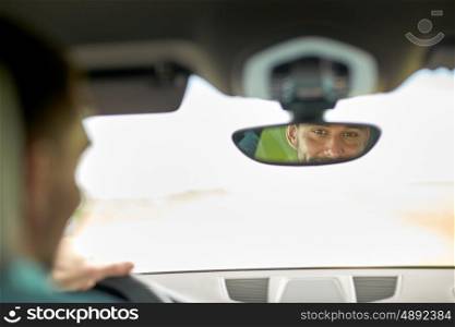 road trip, transport and people concept - rearview mirror reflection of man driving car