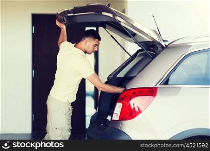 road trip, transport, private property leisure and people concept - young man with open car trunk at parking space