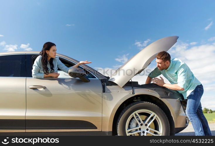 road trip, transport, travel and people concept - family couple with open hood of broken car at countryside