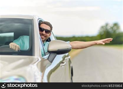 road trip, transport, travel and people concept - happy smiling man in sunglasses driving car and waving hand