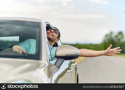 road trip, transport, travel and people concept - happy smiling man in sunglasses driving car and waving hand