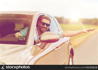 road trip, transport, travel and people concept - happy smiling man in sunglasses driving car and waving hand. happy man in shades driving car and waving hand