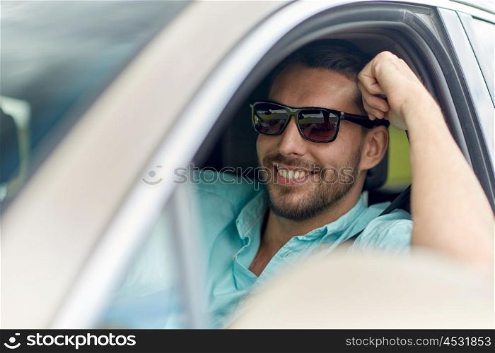 road trip, transport, travel and people concept - happy smiling man in sunglasses driving car