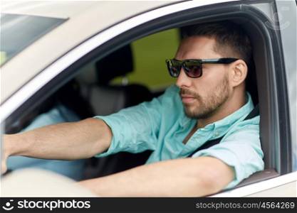 road trip, transport, travel and people concept - young man in sunglasses driving car