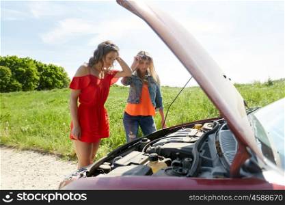 road trip, transport, travel and people concept - young women with open hood of broken car at countryside. women with open hood of broken car at countryside