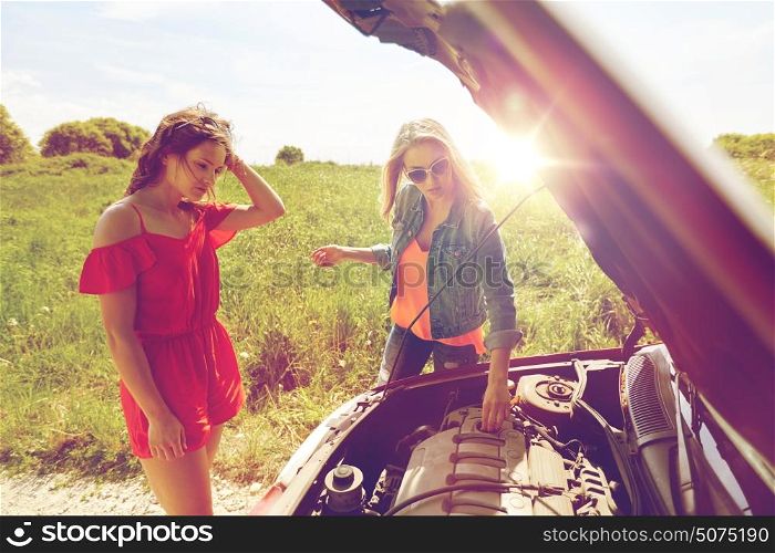 road trip, transport, travel and people concept - young women with open hood of broken car at countryside. women with open hood of broken car at countryside