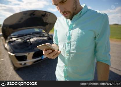 road trip, transport, travel, technology and people concept - close up of man with smartphone and broken car. close up of man with smartphone and broken car